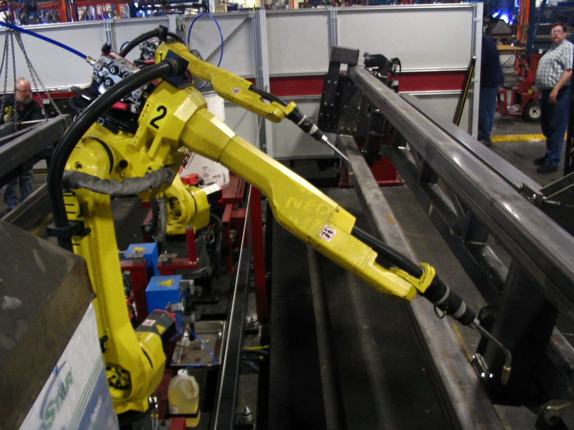 FANUC six-axis welding robots in a manufacturing cell — illustrative